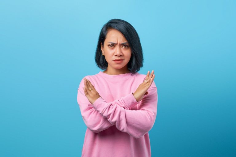 a woman in a pink sweater is holding her hands together