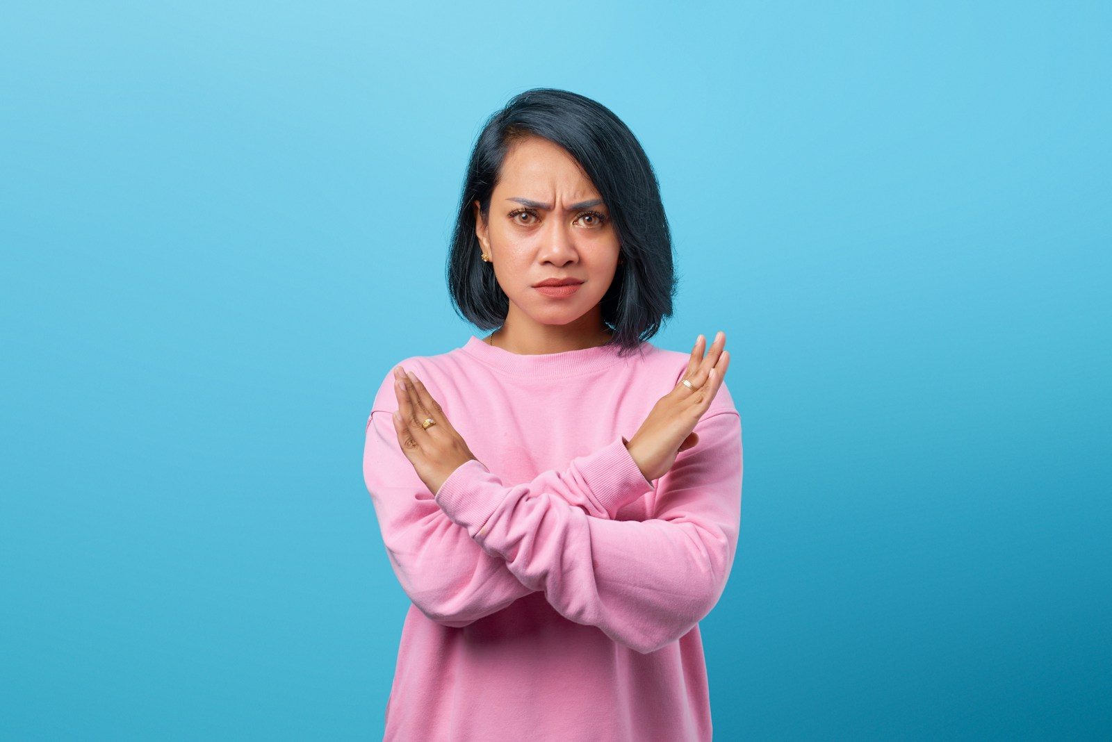 a woman in a pink sweater is holding her hands together