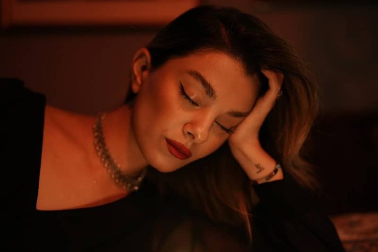 woman with eyes closed resting her head in her left ahnd